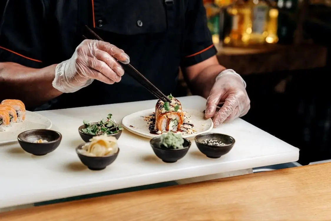 Sumo-Sushi-Hibachi-Japanese-restaurant-Gourmet-Sushi-Plating-Daytona-Beach Chef plating a beautifully decorated sushi roll with fresh ingredients like microgreens at Sumo Sushi Hibachi, a Japanese restaurant in Daytona Beach